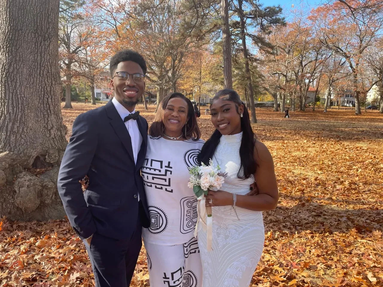 Couple with officiant in an autumn park ceremony